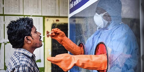 A healthcare worker collects a swab sample of a man for COVID-19 test from the swab collection booth. (Photo | PTI)