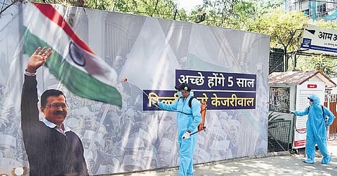 Workers spray disinfectant outside the Aam Aadmi Party office during the nationwide COVID-19 lockdown, in New Delhi on Monday| Parveen Negi