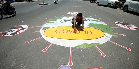 A man draws a message on a road to raise awareness about the spreading of coronavirus disease in Ahmedabad. (File photo| ANI)