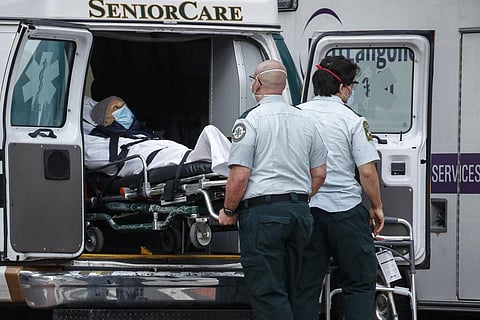 A patient is loaded into the back of an ambulance by medical personnel amid the coronavirus pandemic. (Photo | AP)