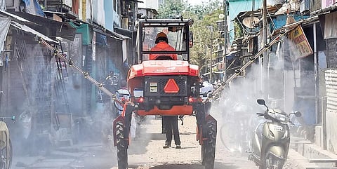 A firefighter decontaminates a road using a boom sprayer at Dharavi in Mumbai | PTI