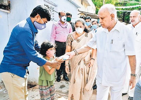 Chief Minister BS Yediyurappa distributes milk packets to residents of Ashwath Nagar, Bengaluru, on Thursday | Express