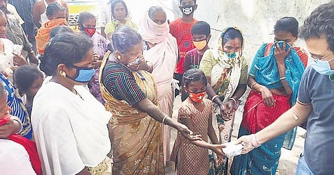 A DIPR volunteer distributes food among migrant workers and their families, in Bengaluru on Thursday | EXPRESS
