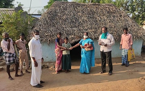 Headmistress Kannagi giving Rs 1000 to a family at Thuppapuram in Ariyalur district. (Express photo)