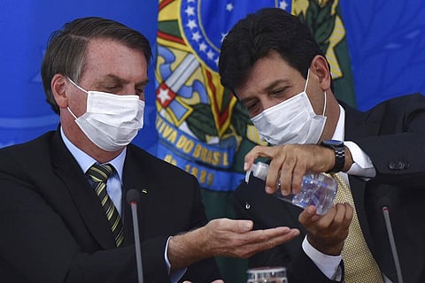 In this March 18, 2019 file photo, Brazil's Health Minister Luiz Henrique Mandetta, right, gives anti-bacterial gel to President Jair Bolsonaro. (Photo | AP)