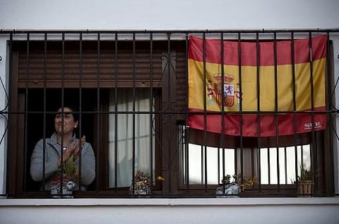 A woman applauds by her window to thank healthcare workers dealing with the COVID-19 coronavirus in Ronda, Spain on April 3, 2020 during a national lockdown to prevent the spread of the COVID-19 coronavirus. (Photo | AFP)