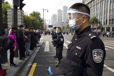 People and policemen bow their heads during a national moment of mourning for victims of coronavirus in Wuhan in central China's Hubei Province, Saturday, April 4, 2020. (Photo | AP)