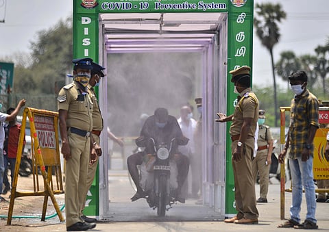 People emerge out from a disinfectant spray system installed by the Greater Chennai Corporation on a road. (Photo | Debadatta Mallick, EPS)