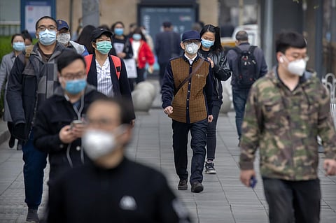 Commuters wear face masks to protect against the spread of new coronavirus as they walk along a street in Beijing, Thursday, April 9, 2020. (Photo | AP)