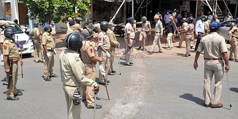 Police personnel stands guard as migrant people clash with the local police as they demand to go to their native places during the ongoing COVID-19 nationwide lockdown, in Surat. (Photo| ANI)