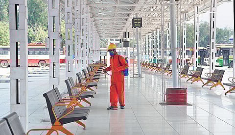 A sanitation worker sprays disinfectant in the waiting area of a bus stand. (File Photo| EPS)