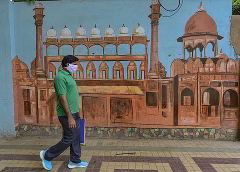 A masked man walks past a wall graffiti depicting Red Fort during the ongoing nationwide COVID-19 lockdown in New Delhi Monday May 11 2020. (Photo | PTI)