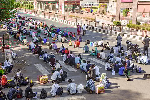 Migrants sit on a street as they wait for city buses to reach a railway station during a nationwide lockdown in the wake of coronavirus pandemic in Surat Sunday May 10 2020. (Photo | PTI)