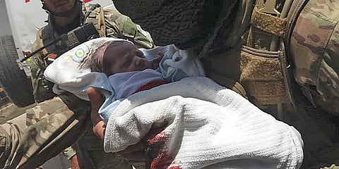 An Afghan security personnel carries a newborn baby from a hospital, at the site of an attack in Kabul. (Photo| AFP)