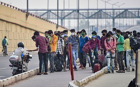 A group of migrants is stopped by a Delhi Police personnel at Delhi-Ghaziabad border while they were walking towards Kanpur after arriving from Ahmedabad by train to New Delhi Railway Station early morning during the ongoing nationwide COVID-19 lockdown a