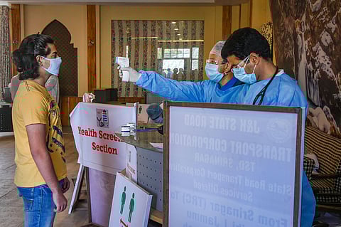 A health official scans the body temperature of a student who was stranded in Delhi on his arrival in Kashmir during the ongoing nationwide lockdown in Srinagar Thursday May 7 2020. (Photo | PTI)