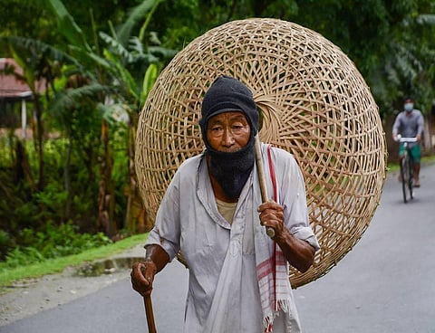 An elderly man walks to a market to sell bamboo baskets during ongoing COVID-19 lockdown at Baganpara in Baksa district of Assam Sunday. (Photo | PTI)