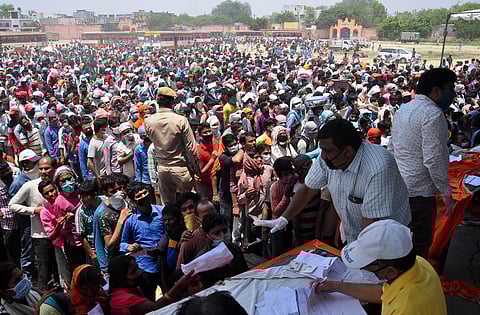 Migrants wait to board buses to reach Ghaziabad railway station as part of their journey to travel to their native places during the ongoing COVID-19 nationwide lockdown at Ramlila ground in Ghaziabad. (Photo | EPS)