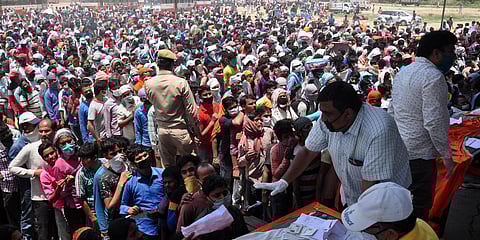 Migrants wait to board buses to reach Ghaziabad railway station as part of their journey to travel to their native places during the ongoing COVID-19 nationwide lockdown at Ramlila ground in Ghaziabad. (Photo | EPS)