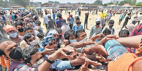 Migrants stretch out their hands for drinking water being distributed by a volunteer at Ramlila ground in Ghaziabad, Uttar Pradesh, on Monday | PTI