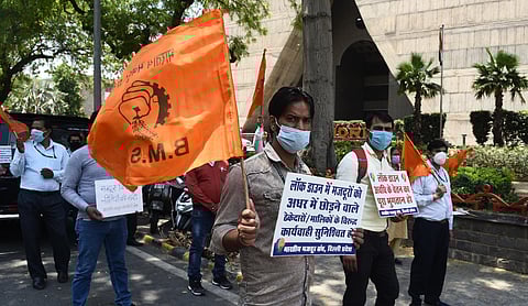 Members of Bharitya Mazdoor Sangh BMS hold placards and shout slogans during a protest over various demands at Palika Kendra in New Delhi on Wednesday. (Photo | Parveen Negi/EPS)