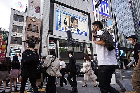 A public screen shows Japanese Prime Minister Shinzo Abe speaking at a press conference. (Photo | AP)
