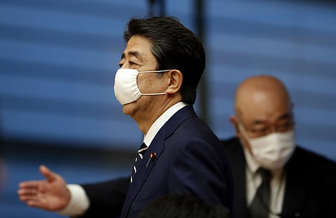 Japan's Prime Minister Shinzo Abe wears a protective mask as he enters a venue for his news conference in Tokyo. (Photo | AP)