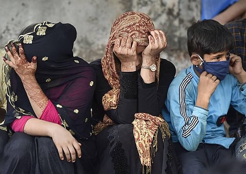 Migrants sit on a pavement outside CSMT as they wait to board a special train to reach their native places during the ongoing COVID-19 lockdown in Mumbai. (Photo | PTI)