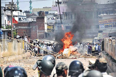 Police keeps a watch at the mob that set barricades on fire at an area along the Rourkela main road on Tuesday (Photo | EPS)