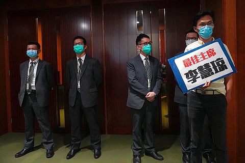 Pro-democracy lawmaker Eddie Chu, right, holds a placard reading 'Best Chairperson, Starry Lee' as he stands outside the chamber of Legislative Council Complex after he was ejected minutes after a second-day legislative debate in Hong Kong Thursday, May 2