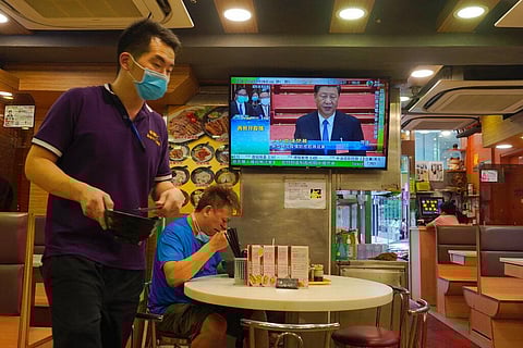 A man has lunch beneath a television showing live telecast of Chinese President Xi Jinping at the closing session of the National People's Congress, in Hong Kong, Thursday, May 28, 2020. China’s ceremonial legislature on Thursday endorsed a national secur