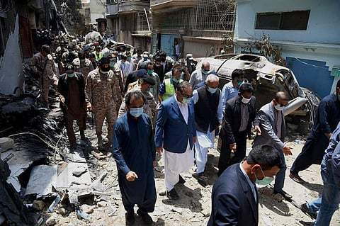 Pakistan Civil Aviation Authority, provincial governor Imran Ismail, center in blue coat, and Pakistan's aviation minister Ghulam Sarwar, center in black waistcoat, visit the site of Friday's plane crash, in Karachi. (Photo | AP)