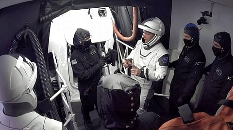In this Wednesday, May 27, 2020 image from video made available by SpaceX, NASA astronauts Doug Hurley, center, and Bob Behnken, left, confer with technicians after leaving the Crew Dragon capsule at the Kennedy Space Center in Cape Canaveral, Fla., after