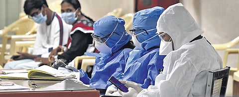 Gandhi Hospital staff at the help desk wearing safety gear, as citizens await COVID-19 tests. (Photo | Vinay Madapu, EPS)