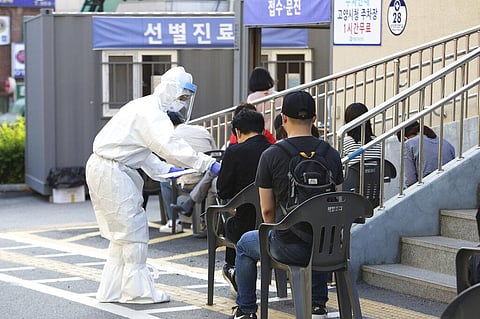 A health official wearing protective gear gives surveys to people waiting for the COVID-19 test at a public health center in Goyang, South Korea, Thursday, May 28, 2020. (Photo | AP)