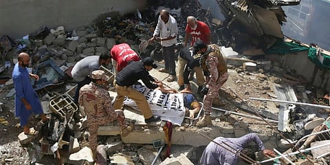 Volunteers cover the dead body of a plane crash victim at the site of the crash in Karachi, Pakistan. (Photo | AP)