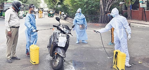 Heath workers in PPE kits spray disinfectant while sanitising vehicles outside Lok Nayak Jai Prakash Hospital | Parveen Negi