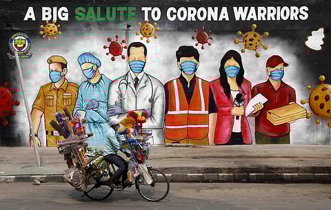 A cyclist paddles infront of a graffiti which is dedicated to corona warriors in New Delhi. (Photo | Anil Shakya, EPS)