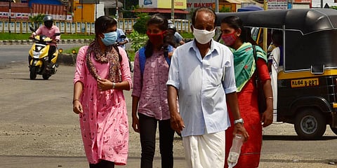 People wearing masks pass by the Statue of the Survivor which was erected by the Koratty police at the NH66. (Photo| Albin Mathew, EPS)