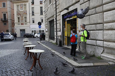 A customer enjoys a pastry outside a bar in Rome, Tuesday, May 5, 2020, as bars reopened but only for take away. Italy began stirring again Monday after a two-month coronavirus shutdown, with 4.4 million Italians able to return to work and restrictions on