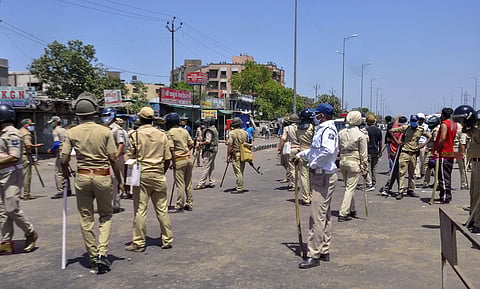 Police personnel stand guard after hundreds of migrant workers seeking to return home clashed with police and pelted stones at them during the ongoing COVID-19 nationwide lockdown in Surat Monday May 4 2020. (Photo | PTI)