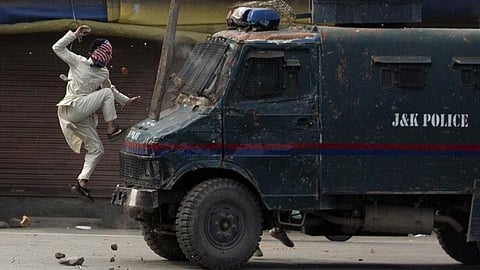 A masked Kashmiri protester jumps on the bonnet of an armoured vehicle of Indian police as he throws stones at it during a protest in Srinagar. (Photo | Dar Yasin, AP)