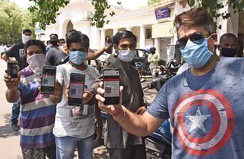 People showing their e-token to purchase liquor during ongoing COVID-19 nationwide lockdown at Gole Market in New Delhi. (photo | Parveen Negi, EPS)