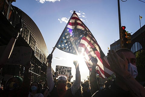 A man holds a U.S. flag upside down, a sign of distress, as protesters march down the street during a solidarity rally for George Floyd, Sunday, May 31, 2020, in the Brooklyn borough of New York. (Photo | AP)