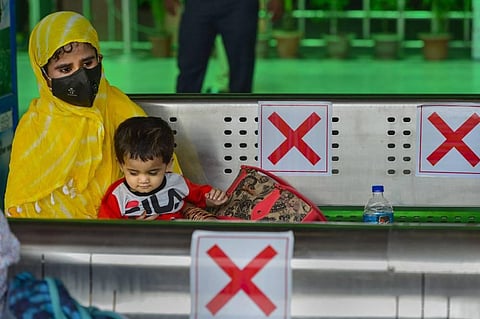 A passenger wearing mask waits along with her son for the arrival of a train at the Nizamuddin Railway Station as Indian Railways resumed operations of 200 passenger trains in New Delhi. (Photo | PTI)
