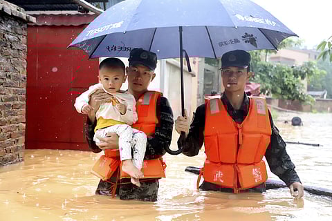Rescuers carry a child to a boat during an evacuation of a flooded village in Qingyuan in southern China. (Photo| AP)