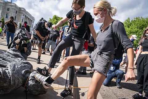 People take turns stomping the Christopher Columbus statue after it was toppled. (Photo | AP)