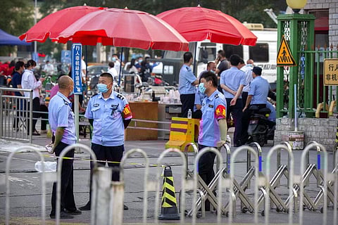 Chinese police stand outside the entrance to a building holding a beef and lamb market in Beijing that was closed by authorities after it was visited by a person who tested positive for COVID-19, Friday, June 12, 2020. (Photo | AP)