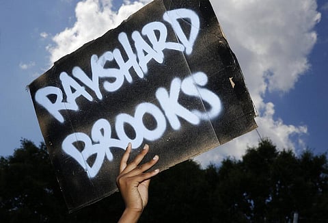 A protester holds up a sign on Saturday, June 13, 2020, near the Wendy's restaurant where Rayshard Brooks was shot and killed by police Friday evening following a struggle in the restaurant's drive-thru line in Atlanta. (Photo | AP)