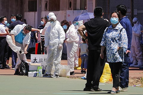 Workers put on protective suits as they wait for people living surrounding the Xinfadi wholesale market arrive to get a nucleic acid test at a stadium in Beijing, Sunday, June 14, 2020. (Photo | AP)